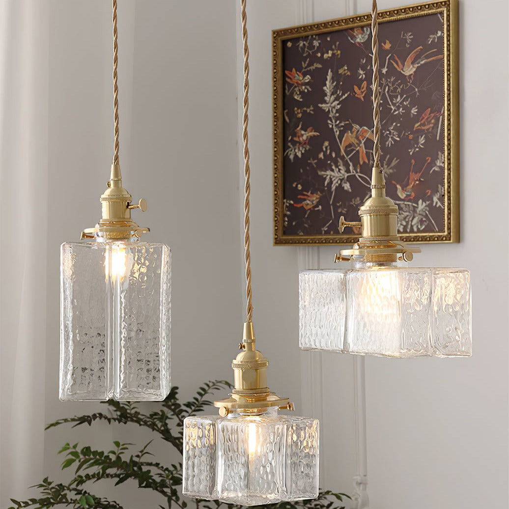 All three Clérachic boxy hammered-glass pendant light shapes lit near a gold-framed floral print and a potted fern.