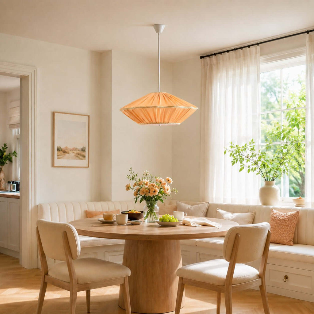 Orange pleated fabric on this Clérachic pendant, hung above a round table in a window-side banquette corner.
