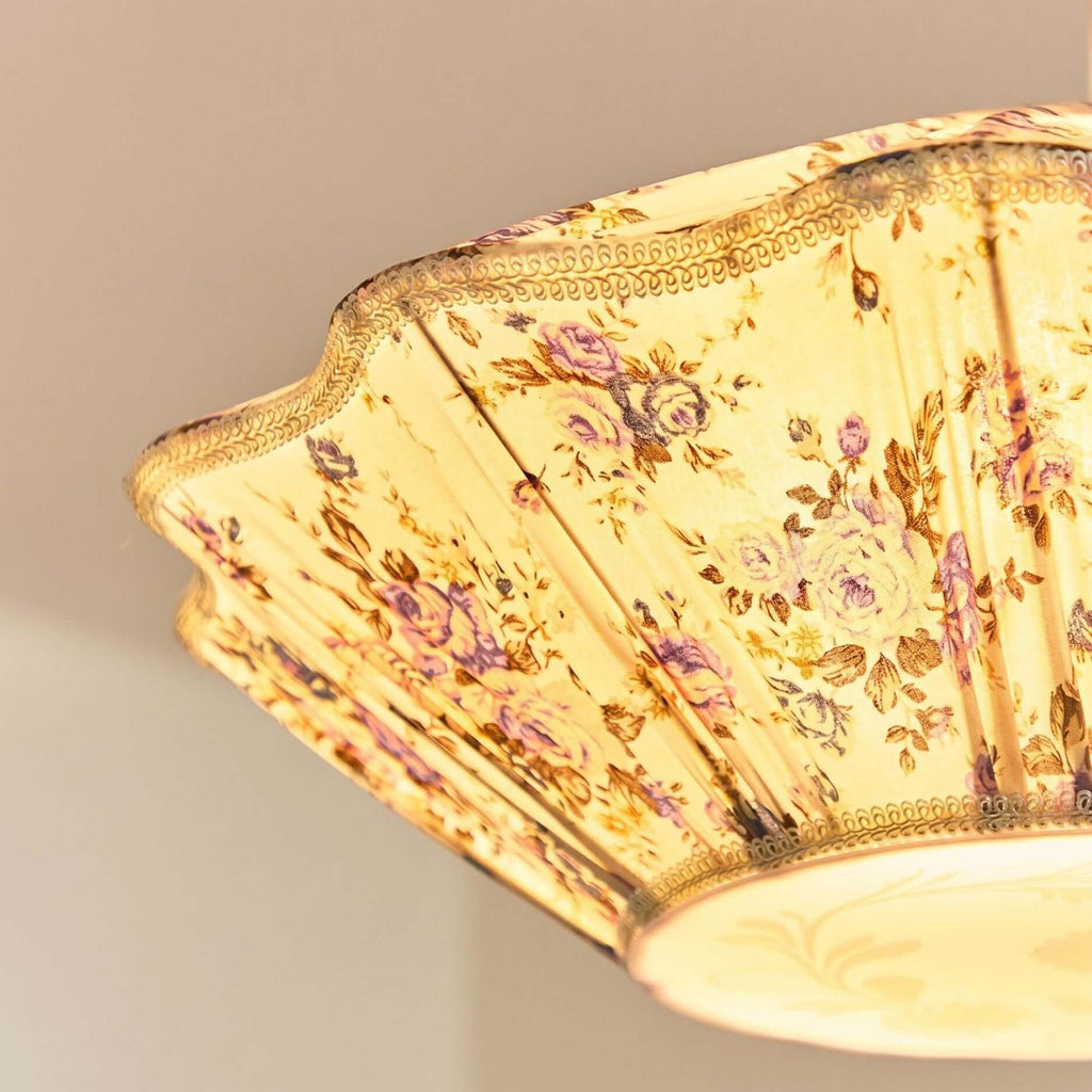 Looking up into the lit shade of this Clérachic pendant, with its scalloped trim, floral pleats and round diffuser.