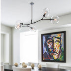 Clérachic branching bubble glass chandelier in black with five clear globes, lit above a dining table in a bright white room.