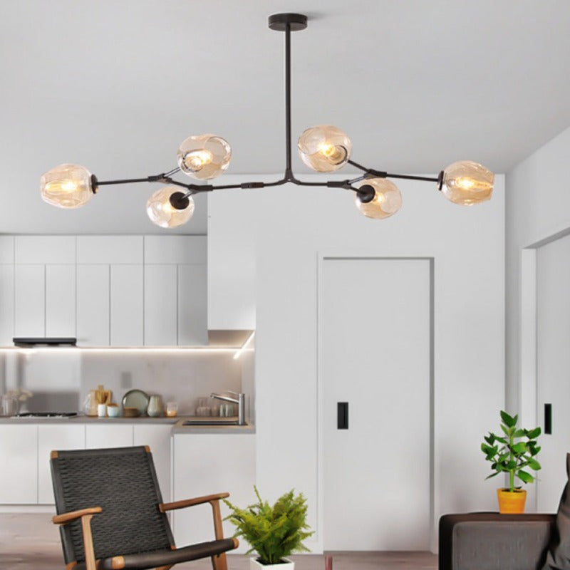 Six amber globes on the black-framed Clérachic chandelier, glowing over an open-plan kitchen and living room.