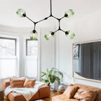 Clérachic chandelier in its five-head size, gradient green globes on black arms, lit above a room of tan leather sofas.