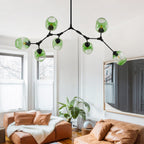 Seven gradient green globes branch from the black Clérachic frame, filling the ceiling above a bright sitting room.