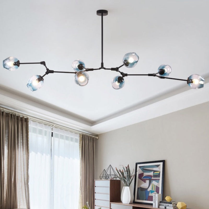 Clérachic chandelier in gradient blue glass on a black frame, lit along a ceiling above a sideboard and curtained window.