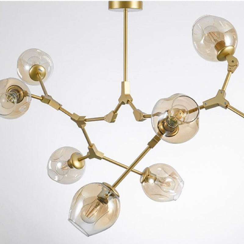Close studio view of the gold Clérachic frame, amber globes sitting mouth-down over their brass lampholders on cranked arms.