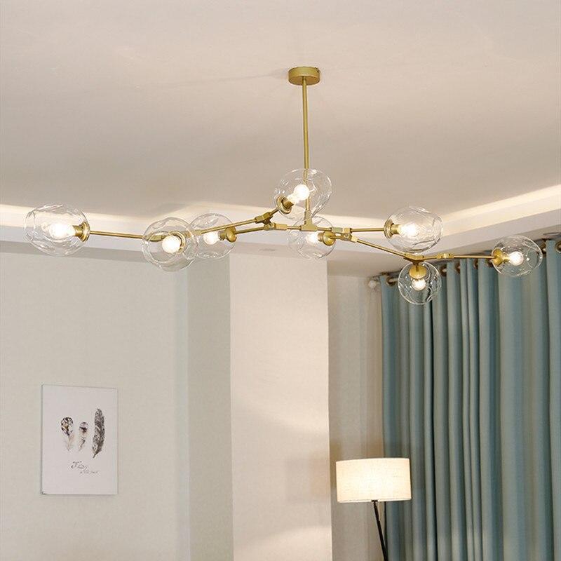 Clear globes on a gold Clérachic frame, lit in a corner beside teal curtains where the arms follow the ceiling line.