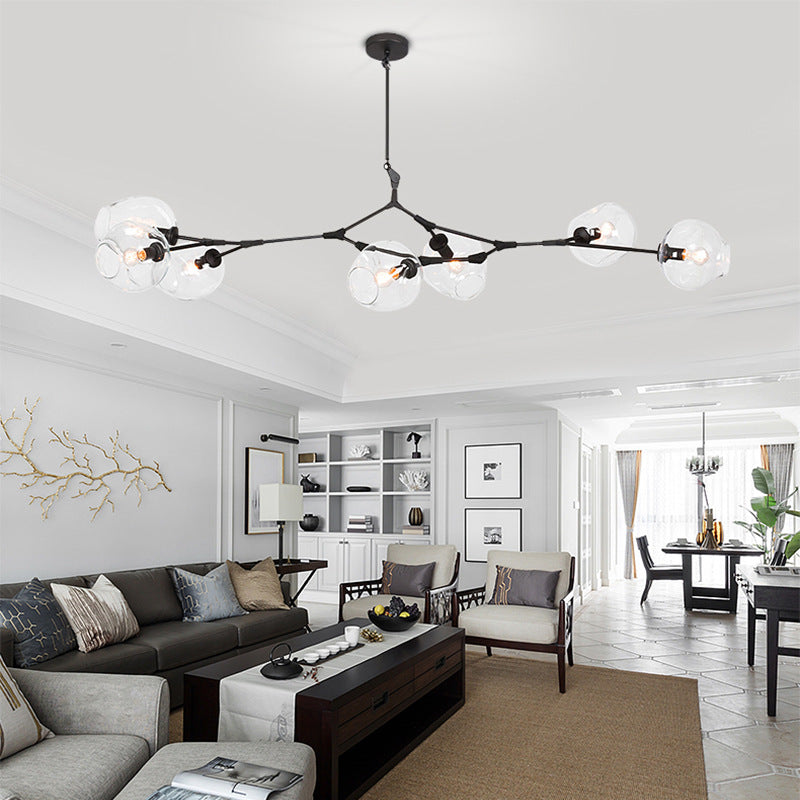 Clérachic chandelier in black with clear glass, spanning the ceiling of a large living room above a sectional and coffee table.