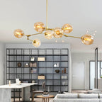 Amber-glass Clérachic chandelier on gold arms, lit above a marble counter with a black grid bookcase behind it.