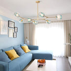 Gradient blue globes on the gold Clérachic frame, hung above a blue sectional sofa in a daylit sitting room.
