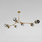 Unlit studio view of the Clérachic chandelier in gradient gray glass on gold arms, the branching shape read against grey.