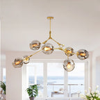 Smoke globes on the gold Clérachic chandelier, lit in a white room whose windows look out over open water.