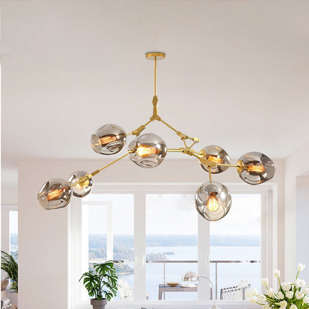Smoke globes on the gold Clérachic chandelier, lit in a white room whose windows look out over open water.