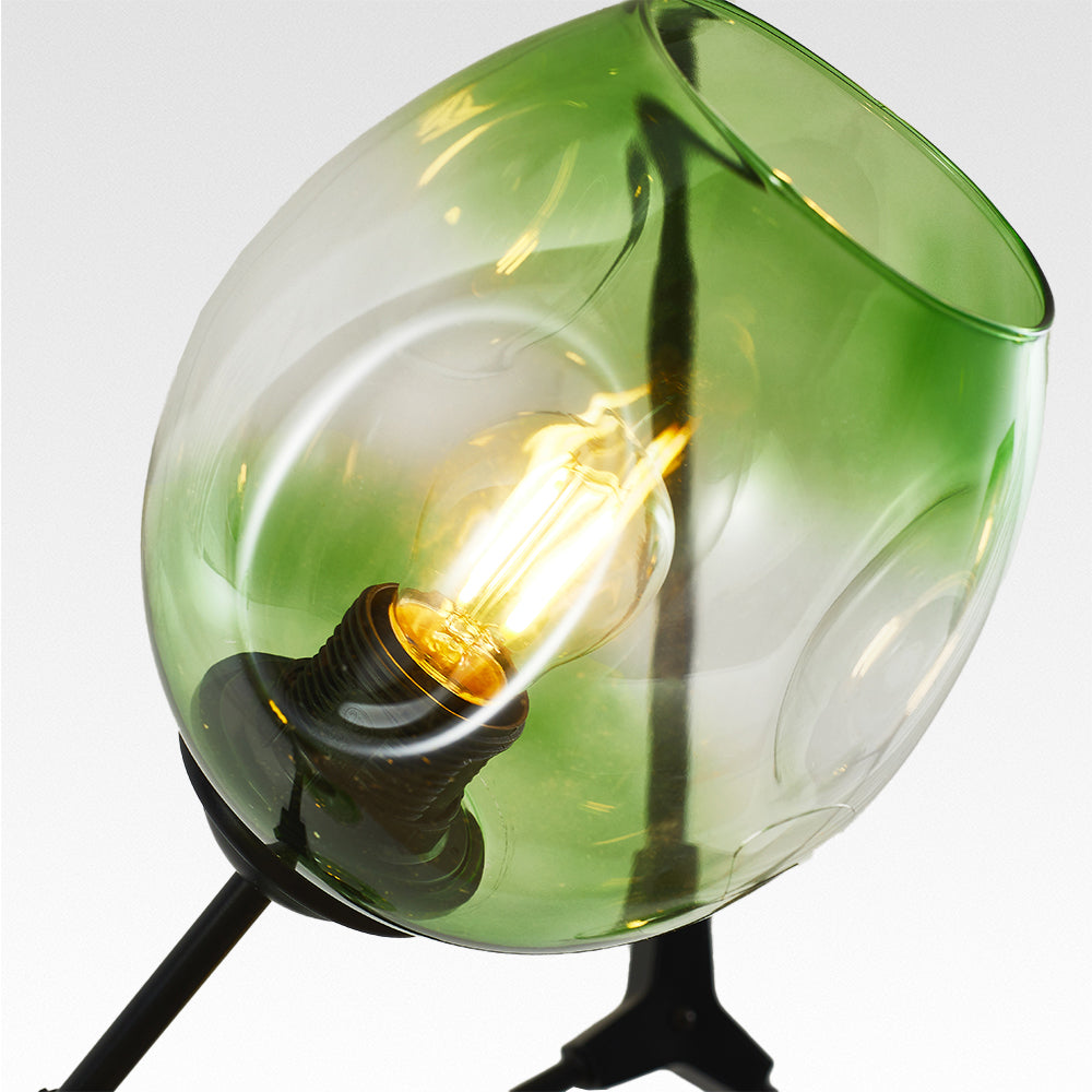 Close view of one Clérachic globe: hand-blown dimpled glass, open at the top, with the filament bulb showing through the green.