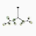 The nine-head Clérachic chandelier at its full 220 cm span, gradient green globes on black arms against a studio white ground.