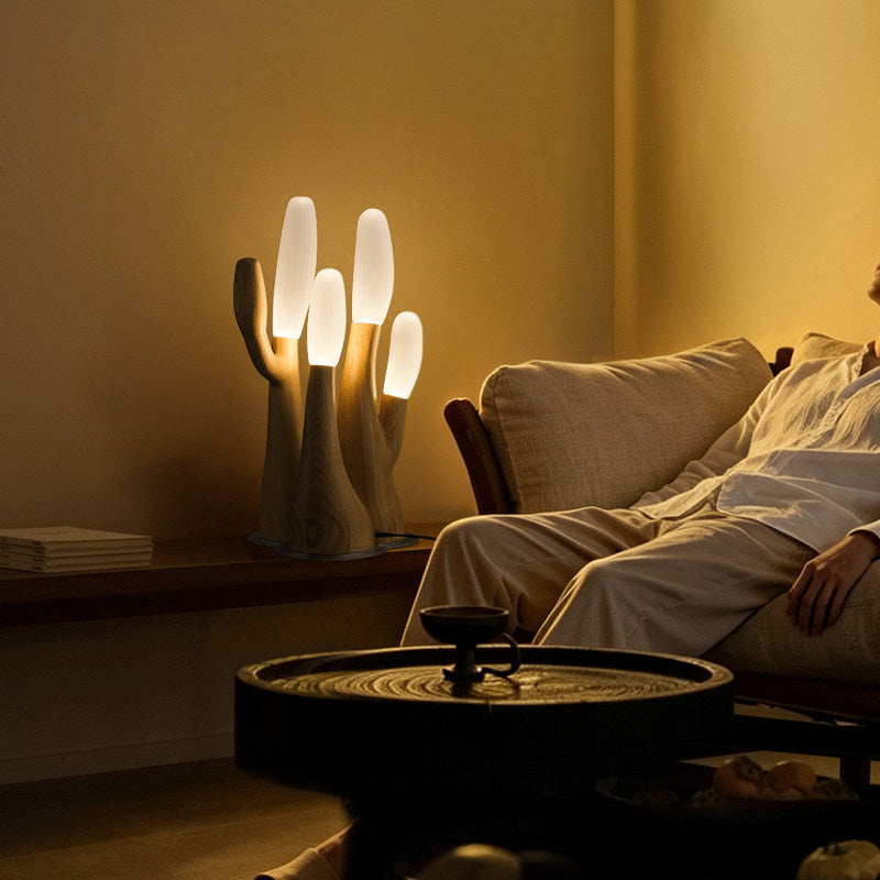 Lit beside a low daybed, this light-wood Clérachic table lamp sits on a round side table in a warm room.