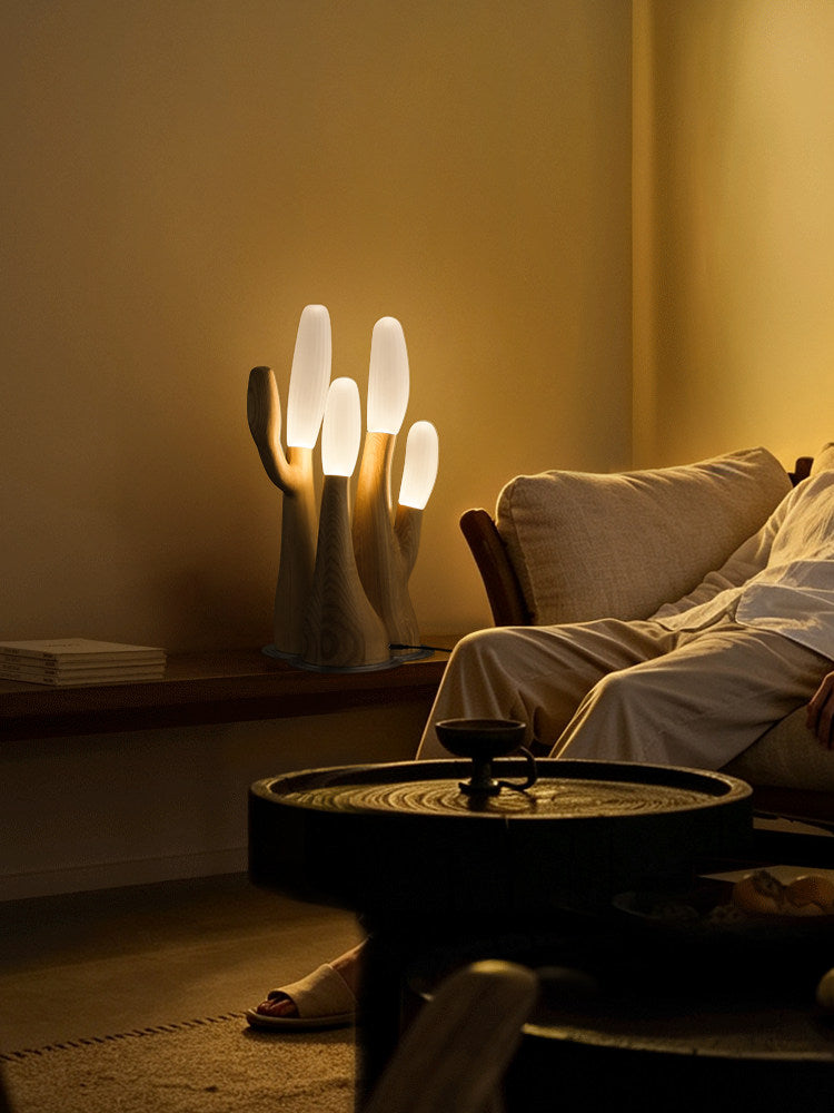 This light-wood Clérachic table lamp lights a round side table beside a sofa draped with a throw.