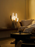 This light-wood Clérachic table lamp lights a round side table beside a sofa draped with a throw.