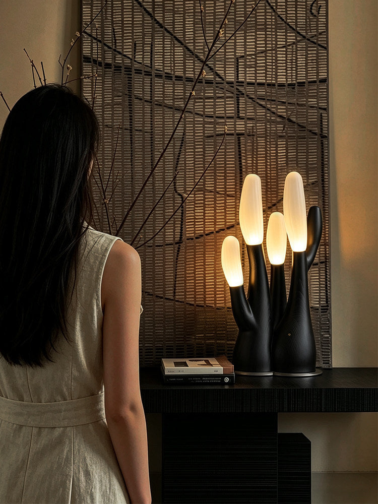 Viewed from further back, this black Clérachic table lamp glows on a console table beside a woven wall panel.