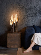 This dark-wood Clérachic table lamp lights a wood crate beside a navy sofa against a textured wall.