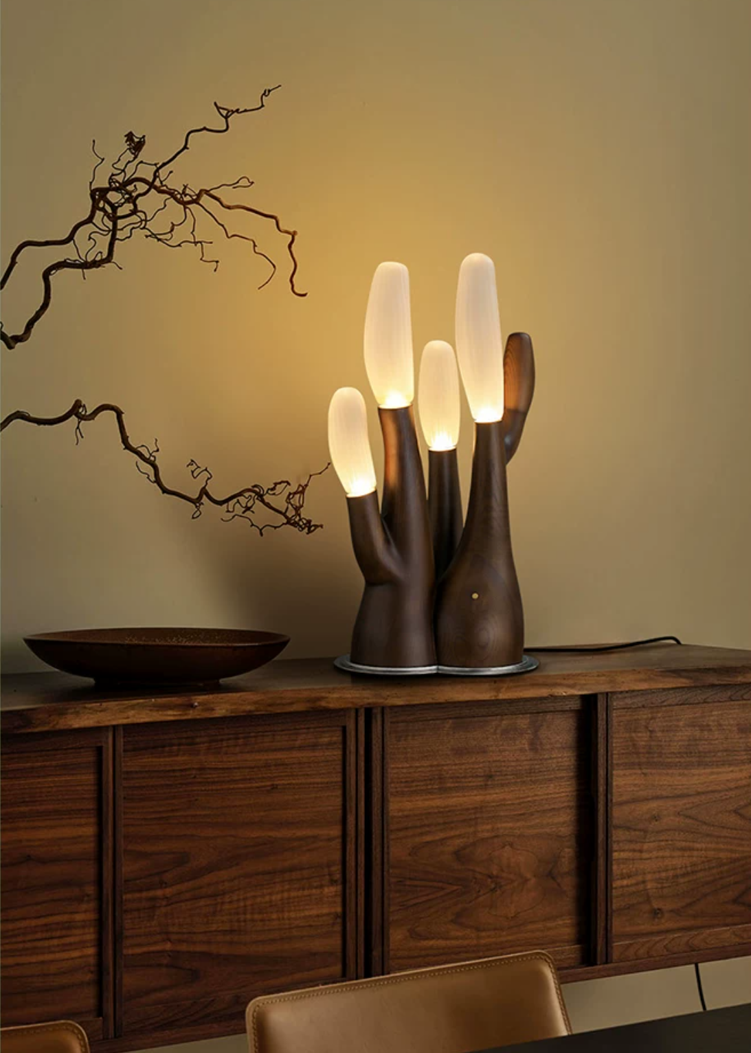 This dark-wood Clérachic table lamp glows on a walnut sideboard beside a bowl and bare branches.