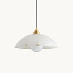This Clérachic pendant on a plain white backdrop, with a veined white alabaster dome, a brass cap and a black cord above a round bulb.