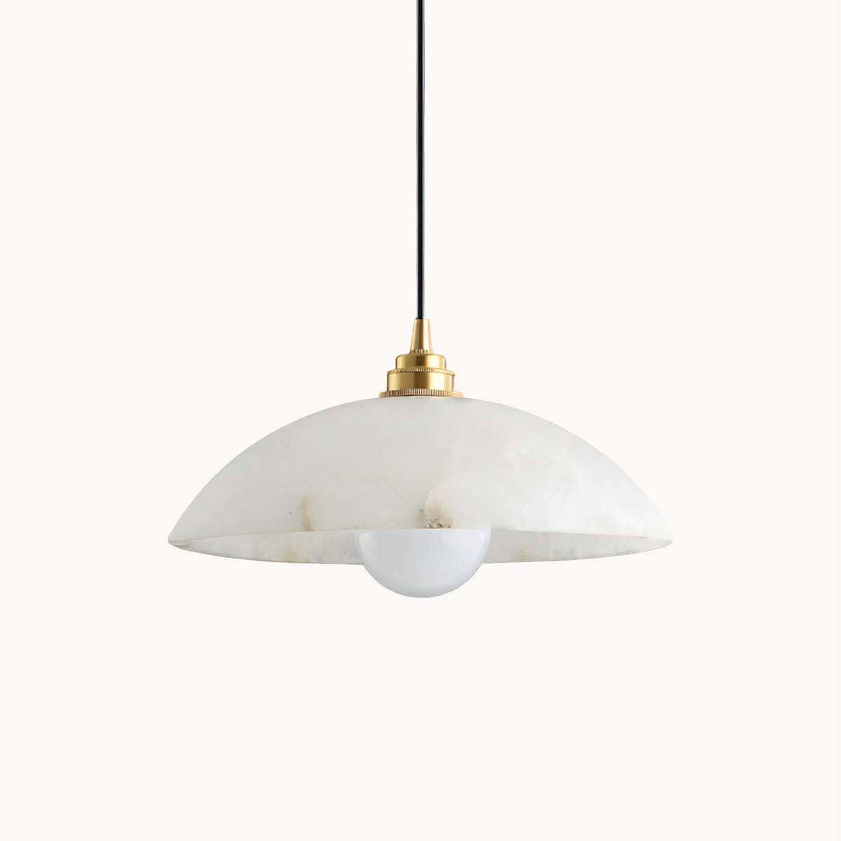 This Clérachic pendant on a plain white backdrop, with a veined white alabaster dome, a brass cap and a black cord above a round bulb.