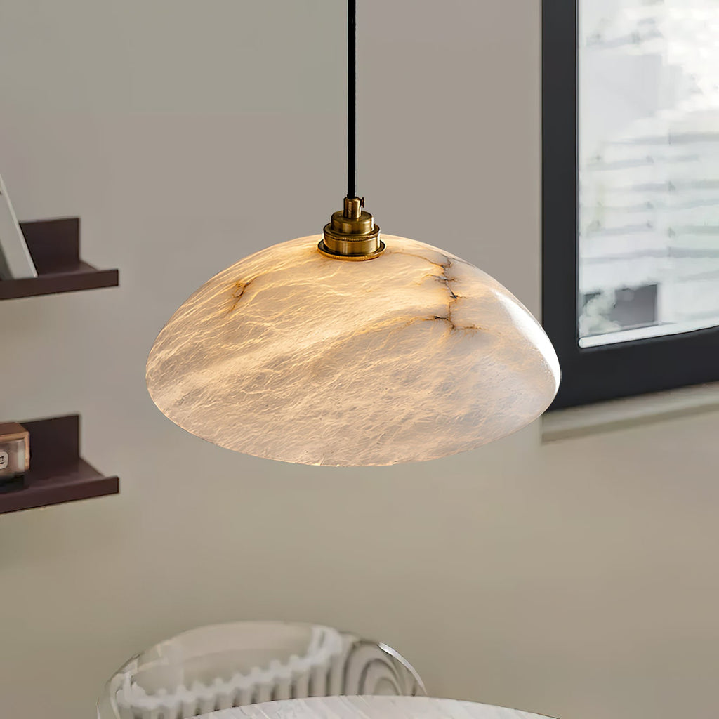Close, low view of the cloudy, veined alabaster of this Clérachic pendant, lit from within, with a brass lamp holder on the black cord.