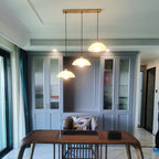 Three alabaster pendants from Clérachic on one long brass canopy, hanging at staggered heights above a wooden desk in a study.