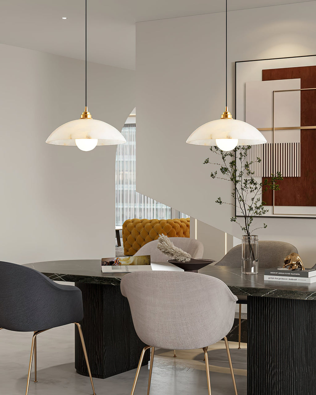 Two Clérachic alabaster pendants over a dark dining table with grey upholstered chairs, in a room with a large abstract artwork.