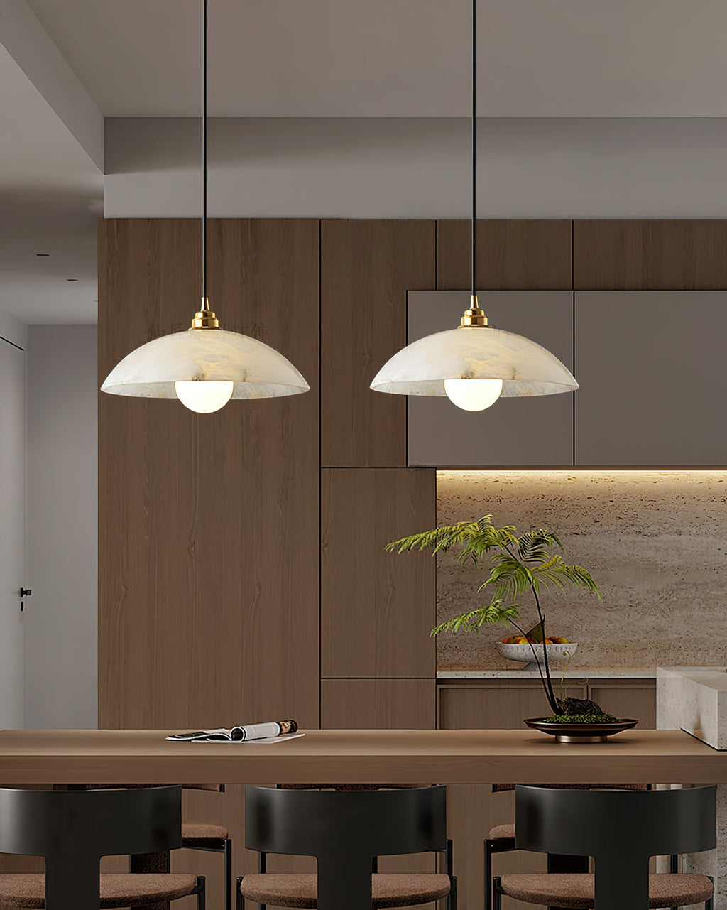 Two Clérachic pendants with white alabaster domes hanging above a wooden counter with bar stools, in front of a warm timber kitchen wall.