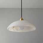 Clérachic pendant with a veined alabaster dome, a brass cap and a frosted bulb, photographed against a plain grey wall.