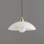 Close side view of a Clérachic alabaster pendant, showing the stepped brass lamp holder and a round opal bulb below the rim.