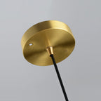 Close view of the round brushed-brass ceiling plate and black cord at the top of this Clérachic pendant.