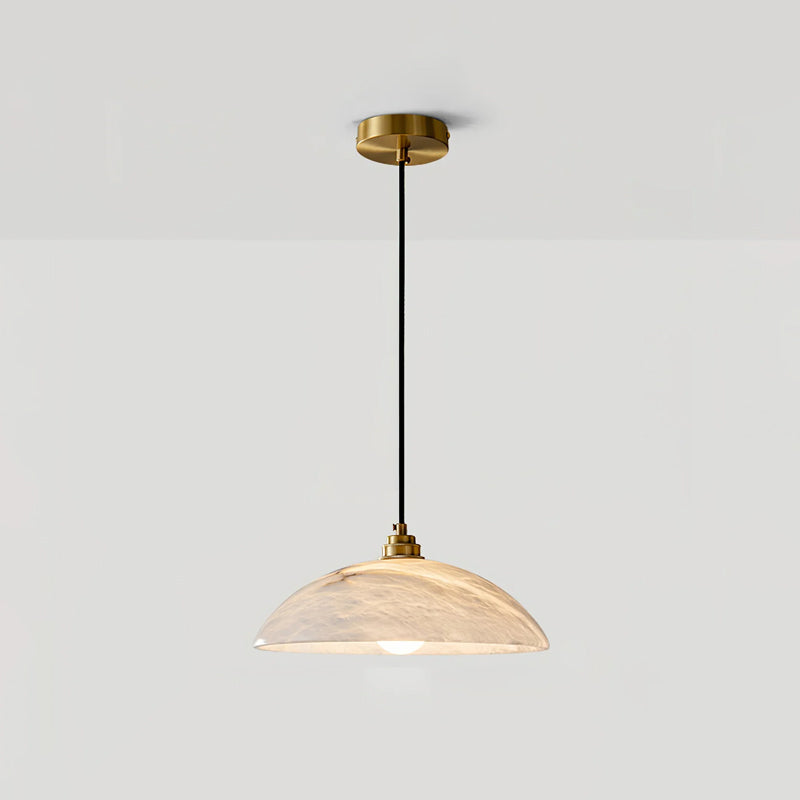 This Clérachic pendant hung from a brass ceiling plate against a pale grey wall, with the alabaster dome glowing in peach tones.