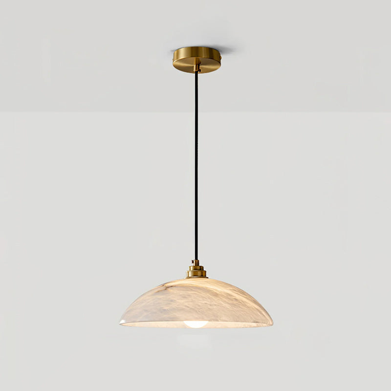 Alabaster dome pendant from Clérachic with a brass ceiling plate, photographed head-on against a pale grey wall with soft warm light.