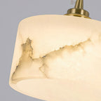 Close view of the natural grey and gold veining in the alabaster shade of this Clérachic pendant, with its brass cap above.