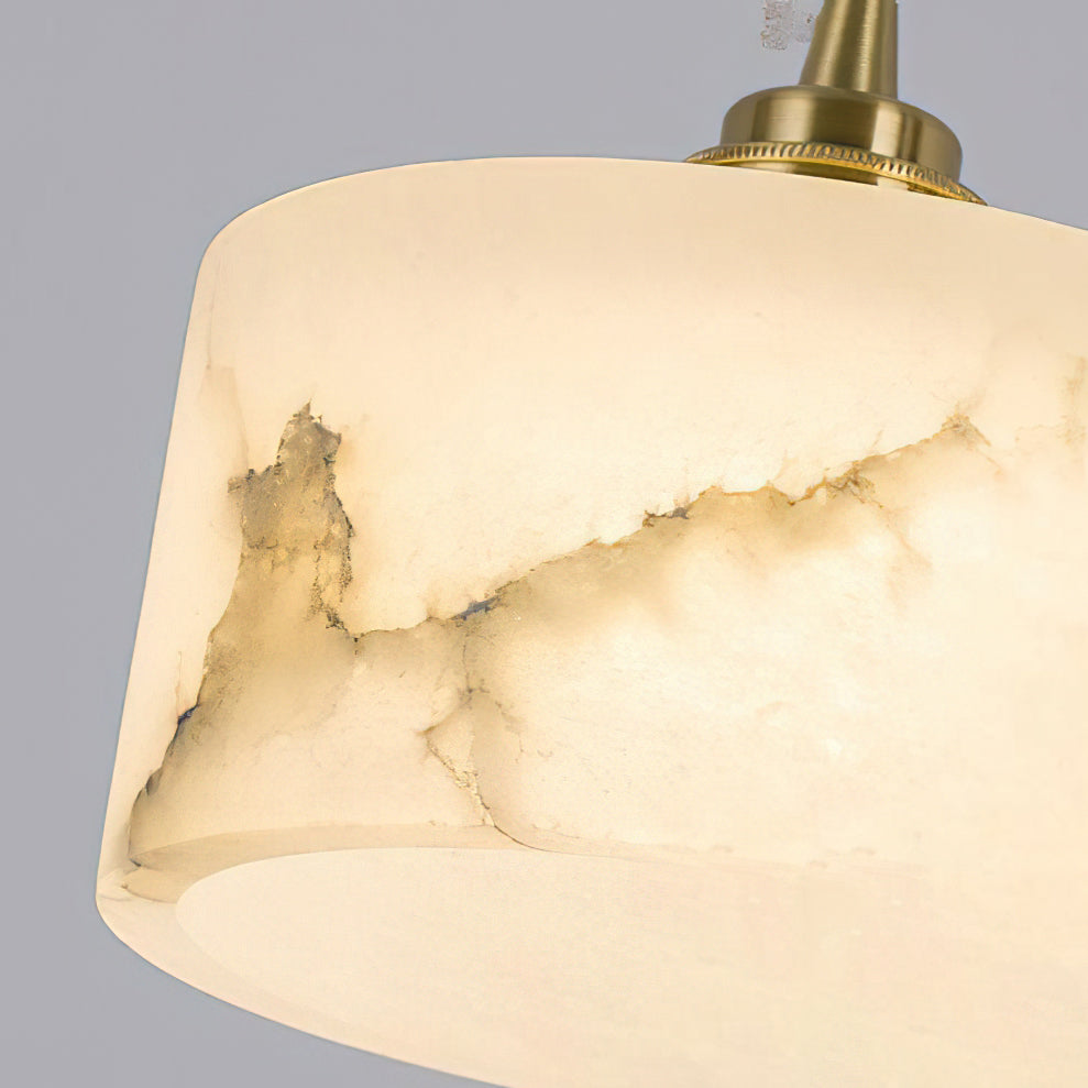 Close view of the natural grey and gold veining in the alabaster shade of this Clérachic pendant, with its brass cap above.