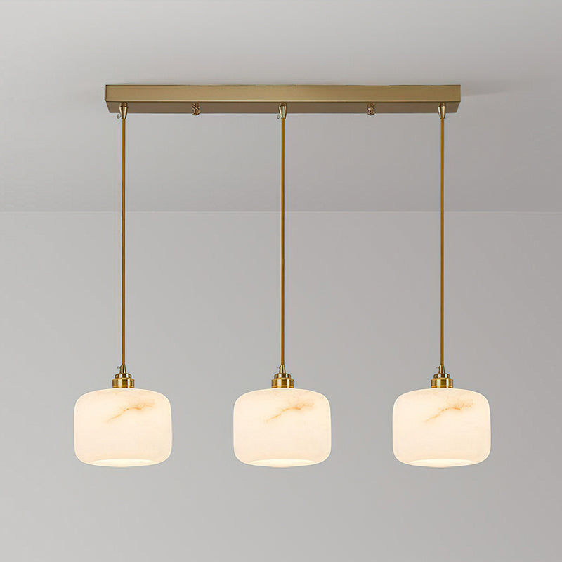 Row of three glowing alabaster pendants from Clérachic, hung evenly from a rectangular brass bar on thin brass rods.