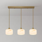 Row of three glowing alabaster pendants from Clérachic, hung evenly from a rectangular brass bar on thin brass rods.