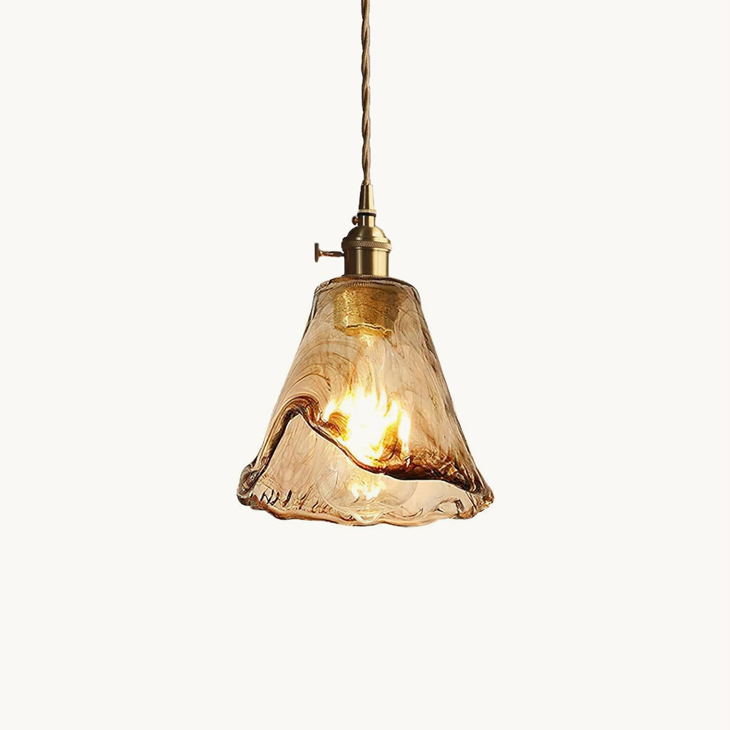 This Clérachic pendant light on a plain white backdrop, with a rippled amber glass shade, a brass switch holder and a twisted cord.