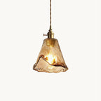 This Clérachic pendant light on a plain white backdrop, with a rippled amber glass shade, a brass switch holder and a twisted cord.