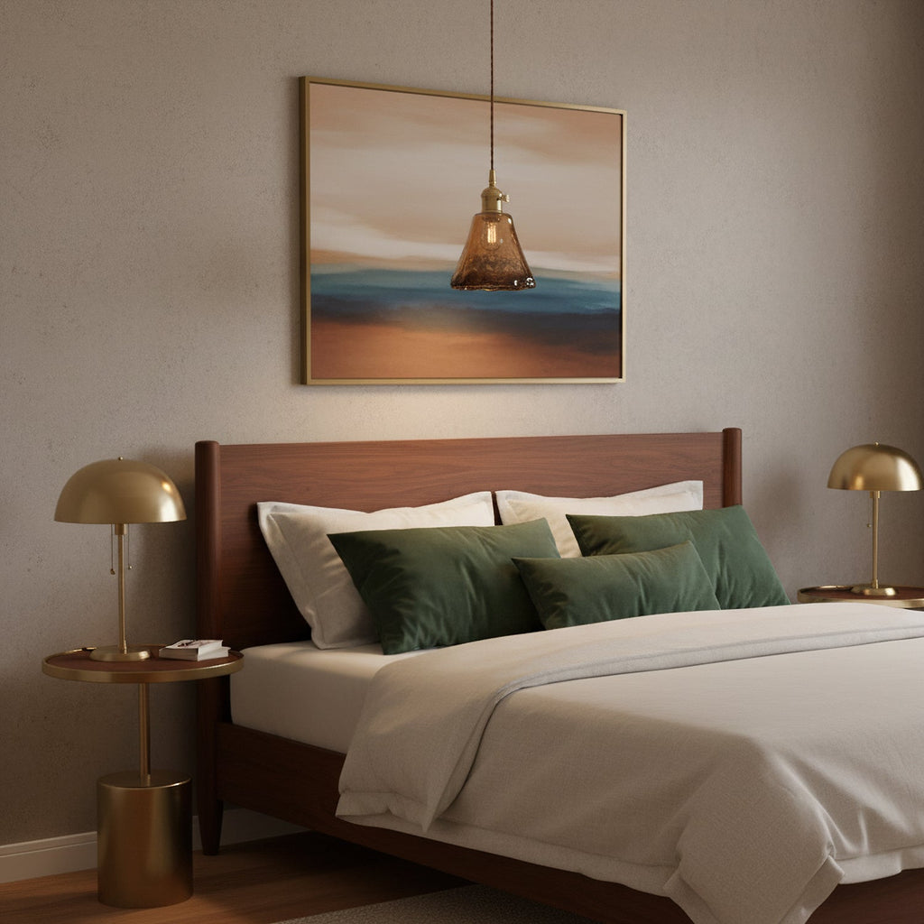 This Clérachic amber pendant hangs above a bed with green cushions, in front of a framed seascape and between two brass bedside lamps.