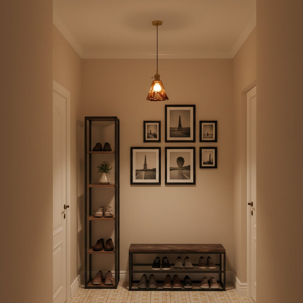 Clérachic amber pendant lit in a small hallway, above a shoe rack, a bench and a group of black-framed prints.