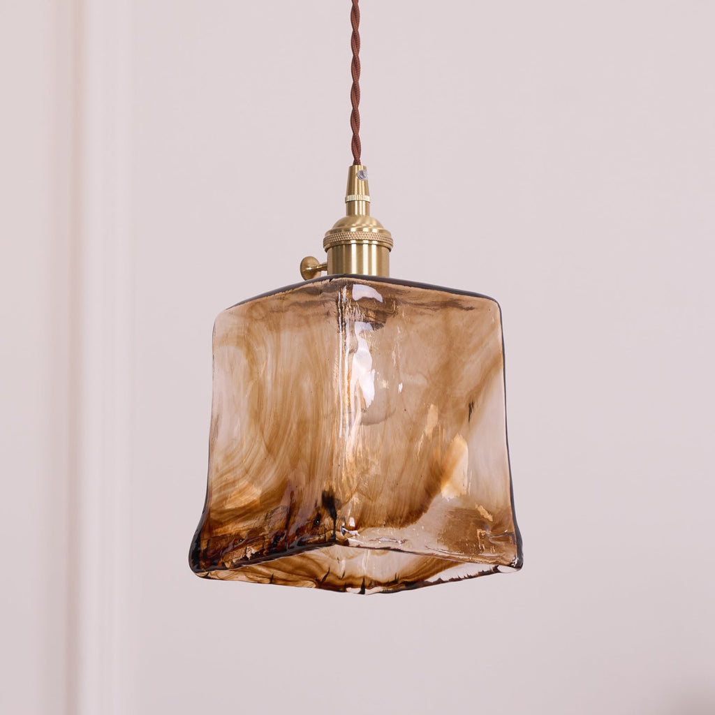 Close view of the squared amber glass shade on this Clérachic pendant, with swirled brown streaks and a thick fused hem.