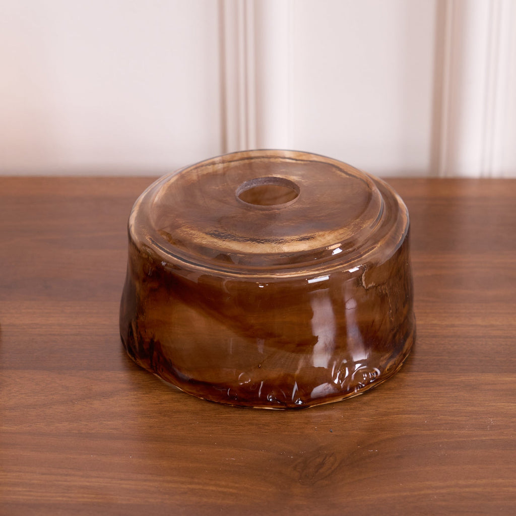 The top of a loose round Clérachic amber glass shade resting upside down on a walnut surface, showing its fitting hole.