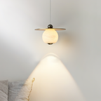 Clérachic Brass and Alabaster Globe Cord Pendant Light lit above a sofa corner, casting a soft cone of light down the wall.