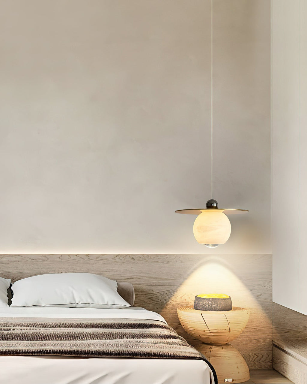 Clérachic Brass and Alabaster Globe Cord Pendant Light lighting a carved wood stool beside a low oak platform bed.
