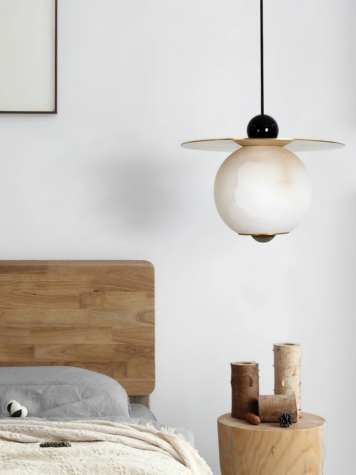 Clérachic Brass and Alabaster Globe Cord Pendant Light unlit over a tree-stump side table stacked with birch logs.