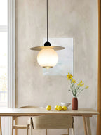 Clérachic Brass and Alabaster Globe Cord Pendant Light above a pale dining table set with lemons and yellow blooms.