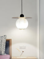 Black gloss finial and brass rim on the Clérachic Brass and Alabaster Globe Cord Pendant Light, lit above a bedside chest.